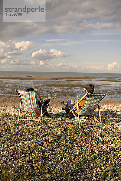 Paar entspannt mit Wein in Strandstühlen am sonnigen Meer