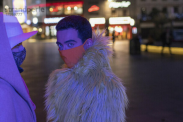 Porträt modischen jungen Mann in Gesichtsmaske auf Stadt Straße in der Nacht