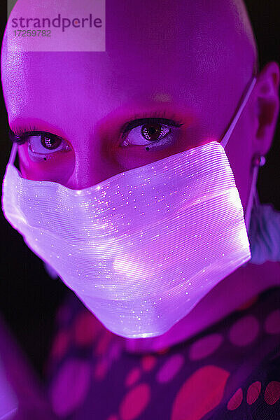 Close up Porträt Frau mit rasiertem Kopf in leuchtenden Gesichtsmaske