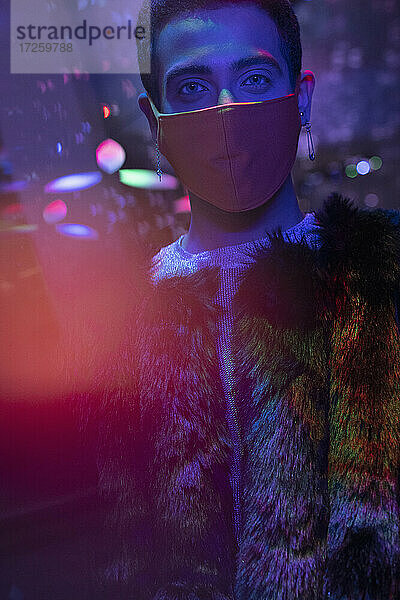 Porträt stilvoller junger Mann mit Gesichtsmaske im Nachtclub