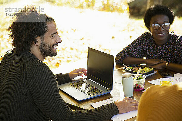Glücklicher Geschäftsmann mit Laptop Treffen mit Kollegen im Park