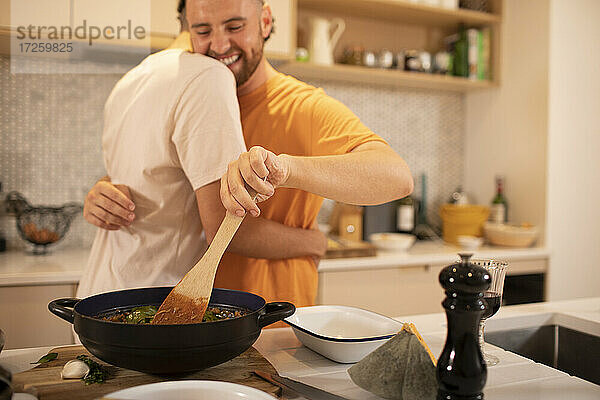 Glückliche Homosexuell männliches Paar umarmen und Kochen in der Küche