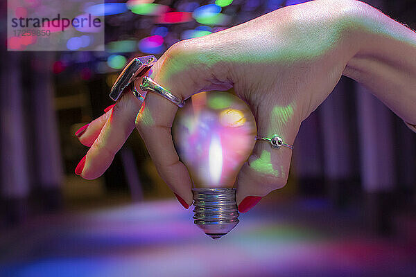 Close up Hand hält Glühbirne unter Neonlicht