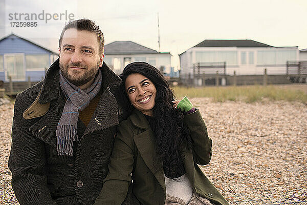 Glückliches Paar in Wintermänteln am Strand