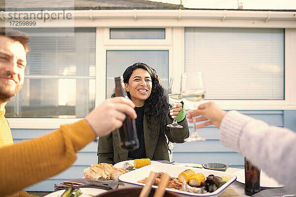 Glückliche Freunde stoßen bei Wein und Bier auf der Terrasse mit Meeresfrüchten an