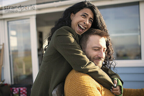 Glückliches liebevolles Paar lachend und umarmend auf der Terrasse