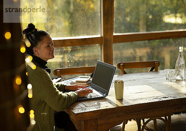 Nachdenkliche Geschäftsfrau arbeitet am Laptop im Café