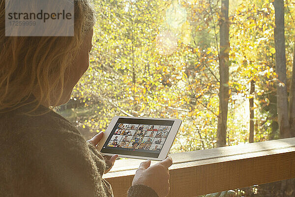 Frau Video-Chat mit Freunden auf digitalen Tablette im Herbst Fenster