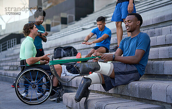 Junger männlicher amputierter Sportler beim Stretching auf der Tribüne