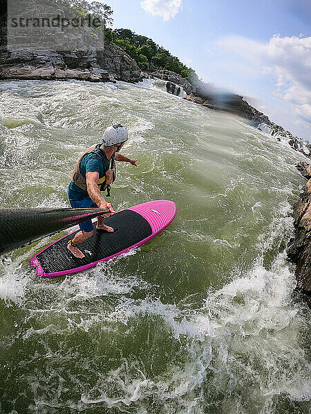 Der Fotograf Skip Brown surft mit dem Stand Up Paddle auf dem anspruchsvollen Wildwasser unterhalb der Great Falls des Potomac River  Grenze zwischen Maryland und Virginia  Vereinigte Staaten von Amerika  Nordamerika