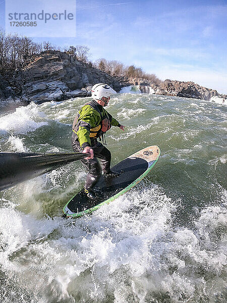 Fotograf Skip Brown beim Stand-Up-Paddle-Surfen im winterlich anspruchsvollen Wildwasser unterhalb der Great Falls des Potomac River  Grenze zwischen Virginia und Maryland  Vereinigte Staaten von Amerika  Nordamerika