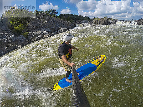Skip Brown surft mit seinem Stand Up Paddleboard im schnell fließenden Wildwasser auf dem Potomac River in der Nähe von Great Falls  Virginia  Vereinigte Staaten von Amerika  Nordamerika