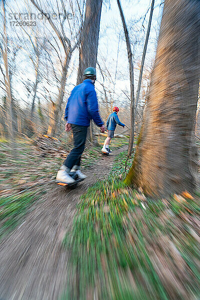 Brüder fahren mit ihren One-Wheels auf einem einspurigen Mountainbike-Trail neben dem Potomac River. Bethesda  Maryland  Vereinigte Staaten von Amerika  Nordamerika