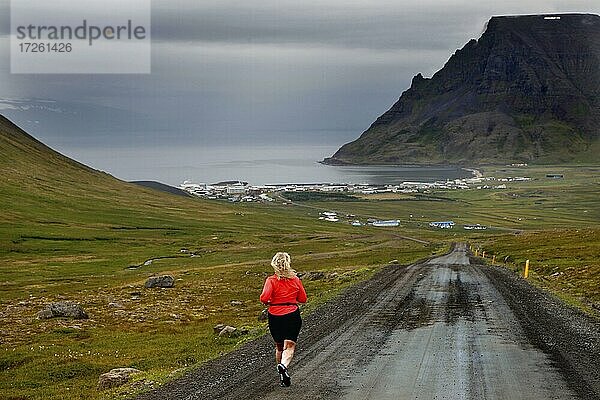 Läuferin  Joggerin  oranges Shirt  Straße  Piste  Schotterweg  Straße von Bolafjall nach Bolungarvik  Bolungarvik  Vestfirðir  Westfjorde  Nord-West-Island  Island  Europa