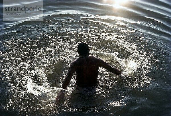 Sonnenaufgang  Mann nimmt eiliges Bad im Ganges Varanasi  Indien  Asien