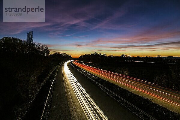 Autos mit Lichtspuren fahren auf eine Schnellstraße kurz nach Sonnenuntergang  Baden-Württemberg  Deutschland  Europa