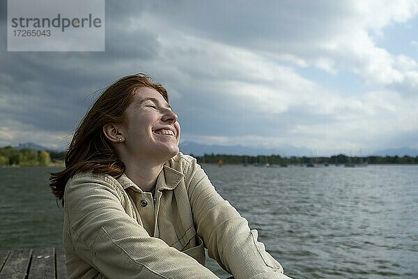 Junge Frau streckt sich glücklich  am See  Starnberger See  Oberbayern  Bayern  Deutschland  Europa