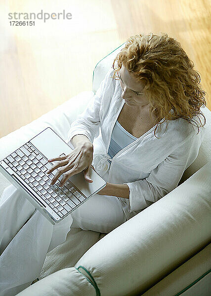 Frau mit Laptop auf Sofa