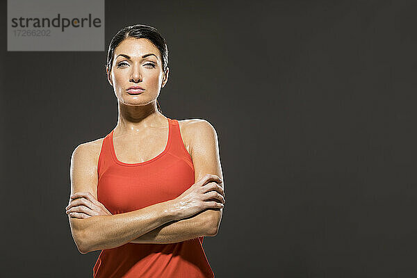 Studio-Porträt einer sportlichen Frau in rotem ärmellosen Oberteil