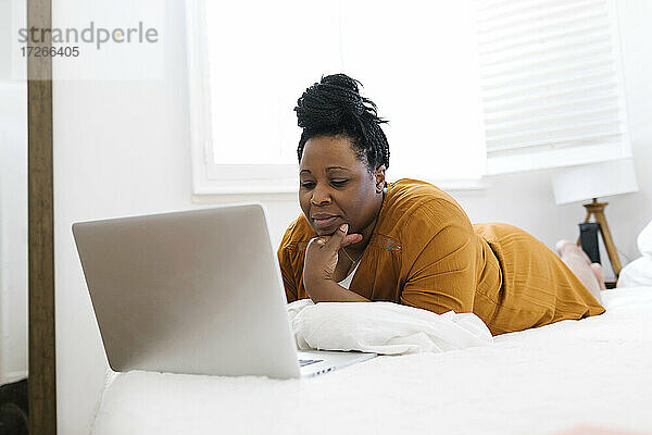 Frau arbeitet am Laptop im Bett