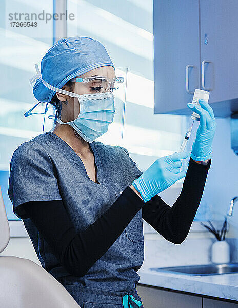 Krankenschwester mit Gesichtsmaske und Schutzschild bereitet Covid-19-Impfung vor