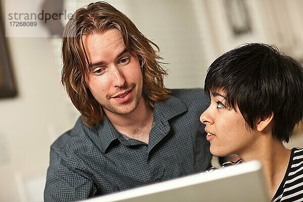 Glücklicher junger kaukasischer Mann und multiethnische Frau verwenden den Laptop-Computer zusammen