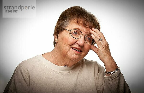 Ältere Frau mit schmerzendem Kopf mit einem dramatischen vignettierten Hintergrund