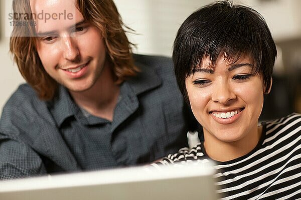 Ziemlich lächelnd multiethnischen Frau und kaukasischen Mann mit einem Laptop-Computer zusammen
