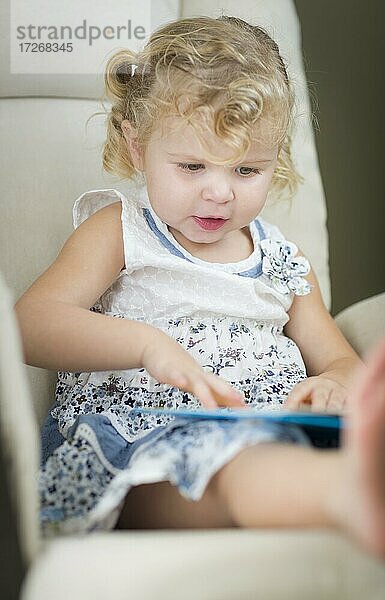 Adorable blondhaarige blaue Augen kleines Mädchen lesen ihr Buch auf dem Stuhl