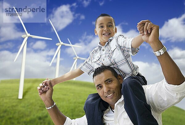 Glücklicher hispanischer Vater und Sohn mit Windradpark über blauem Himmel