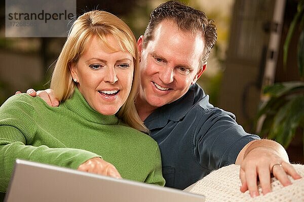 Hübsches glückliches Paar verwendet ihren Laptop zusammen