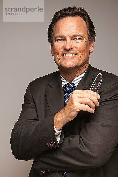 Gutaussehender Geschäftsmann lächelnd in Anzug und Krawatte vor einem grauen Hintergrund