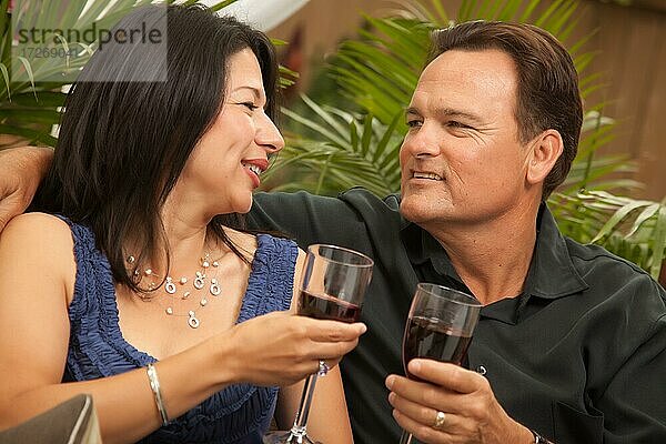 Attraktives hispanisches und kaukasisches Paar trinken Wein draußen