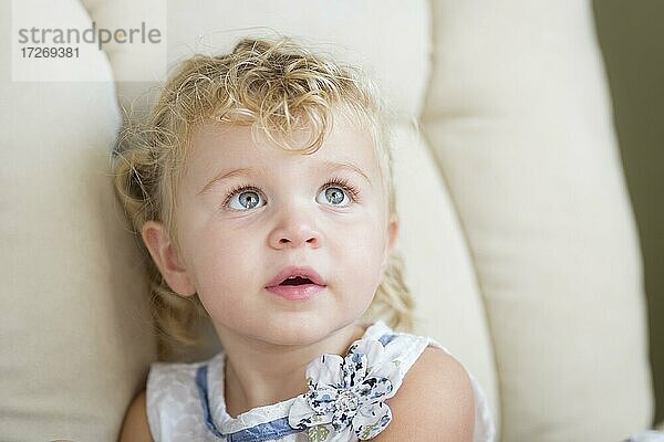 Adorable blonde Haare und blaue Augen kleines Mädchen sitzt im Stuhl