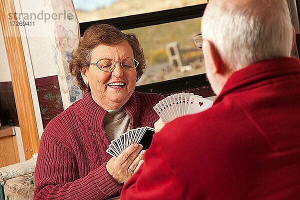 Glückliches älteres erwachsenes Paar spielt Karten in ihrem Wohnwagen Wohnmobil