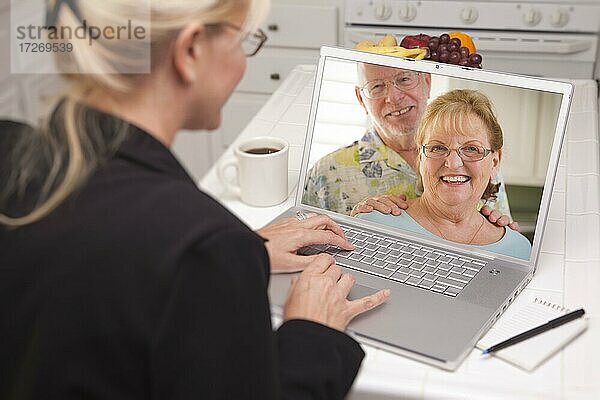 Frau in der Küche mit Laptop  Online-Chat mit älterem Paar oder Eltern auf dem Bildschirm