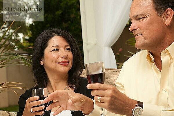 Hispanische Frau und kaukasischer Mann genießen Wein auf der Veranda