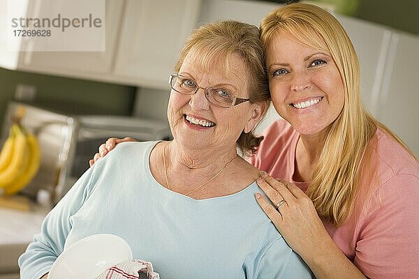 Lächelnde ältere Frau und junge Tochter am Waschbecken in der Küche