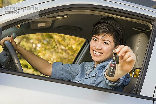 Glücklich lächelnde gemischtrassige Frau im Auto  die einen Schlüsselbund hält