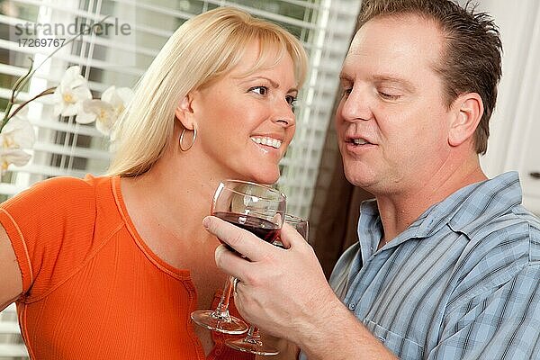 Glückliches Paar  das ein Glas Wein in der Küche genießt