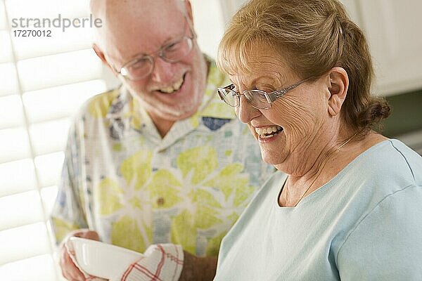 Älteres erwachsenes Paar hat Spaß beim gemeinsamen Abwasch in der Küche ihres Hauses