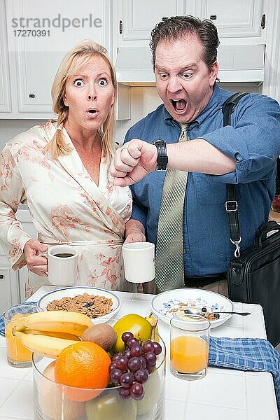 Spät zur Arbeit gestresstes Paar  das die Zeit in der Küche überprüft
