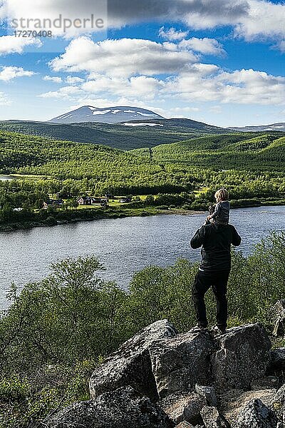 Mann mit ihrem kleinen Baby mit Blick auf den Fluss Karasjohka an der Grenze zwischen Norwegen und Finnland  Lappland  Finnland  Europa