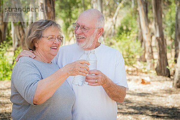 Glückliche gesunde ältere Paar mit Wasserflaschen im Freien