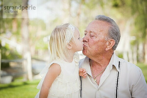 Liebender Großvater und Enkelin küssen draußen im Park