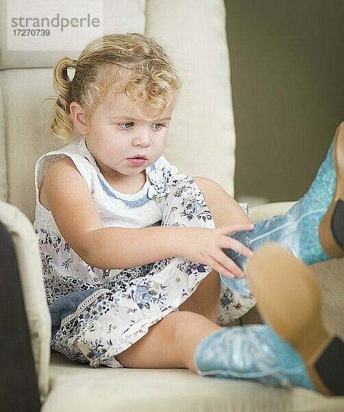 Adorable blonde Haare blauäugige kleine Mädchen setzen auf Cowboy-Stiefel