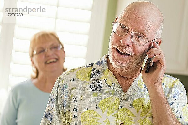 Glückliche Senior erwachsenen Mann am Handy mit Frau hinter in der Küche
