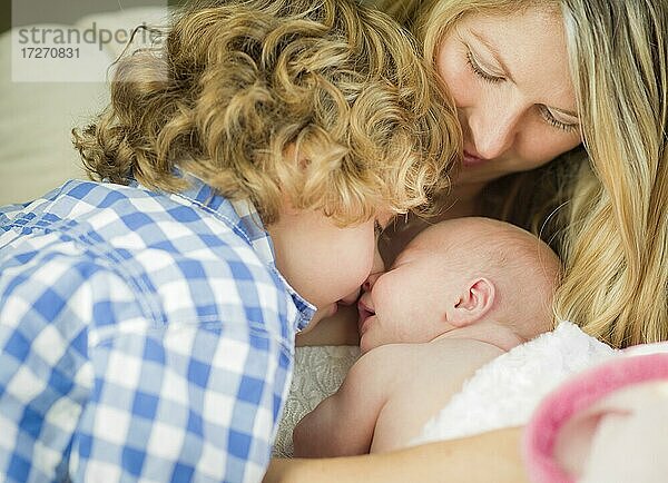 Schöne junge Mutter hält kostbare neugeborenes Baby-Mädchen als Bruder schaut auf