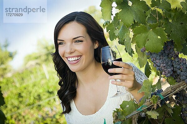 Hübsche gemischtrassige junge erwachsene Frau  die ein Glas Wein im Weinberg genießt