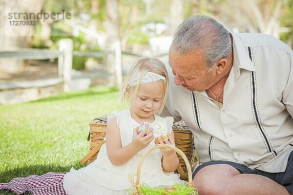 Liebevolle Großvater und Enkelin genießen Ostereier auf einer Picknickdecke im Park